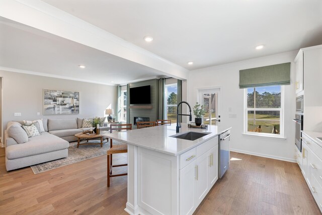 kitchen featuring light hardwood / wood-style floors, a center island with sink, a large fireplace, and sink