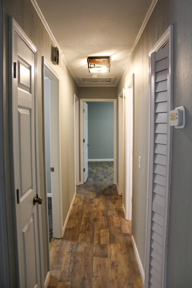 corridor with a textured ceiling, dark hardwood / wood-style floors, and ornamental molding