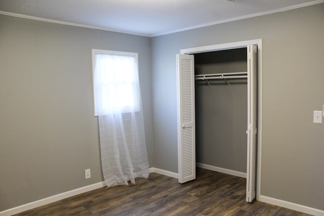 unfurnished bedroom featuring ornamental molding, a closet, and dark wood-type flooring