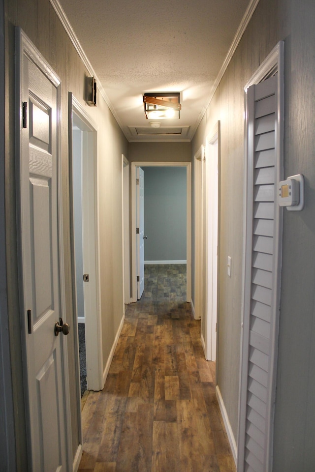 hallway featuring a textured ceiling, crown molding, and dark wood-type flooring