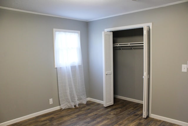 unfurnished bedroom featuring crown molding, a closet, and dark wood-type flooring