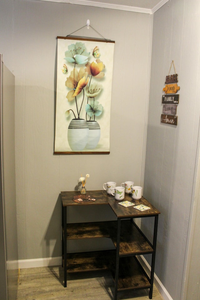 room details with wood-type flooring, ornamental molding, and stainless steel refrigerator