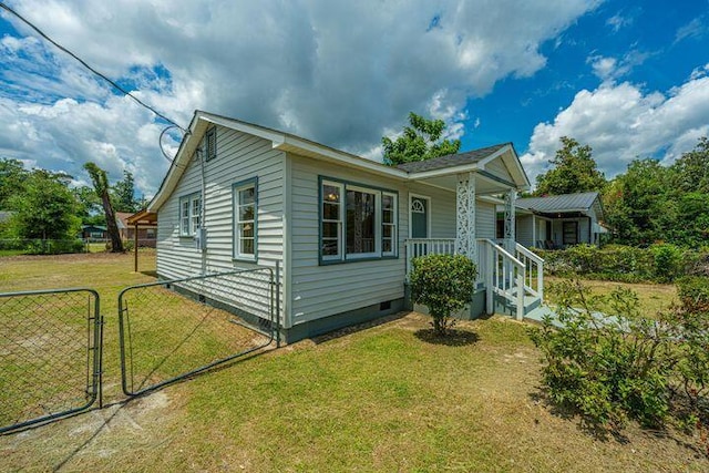 view of front facade with a front lawn, fence, covered porch, crawl space, and a gate