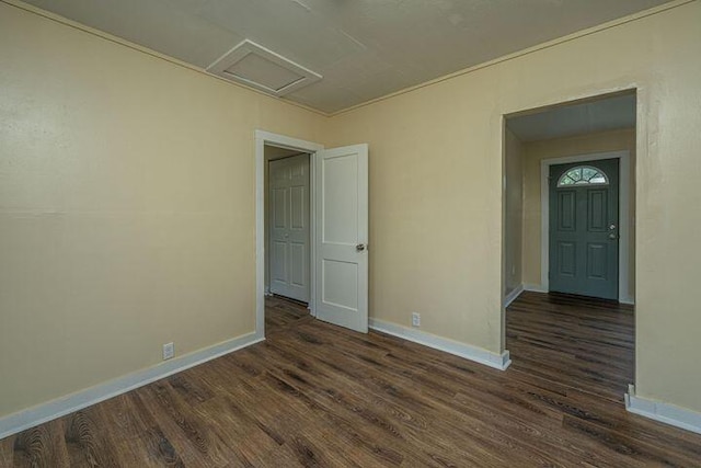 unfurnished room featuring attic access, baseboards, and wood finished floors