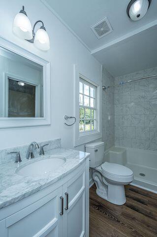 full bath featuring visible vents, toilet, wood finished floors, walk in shower, and vanity