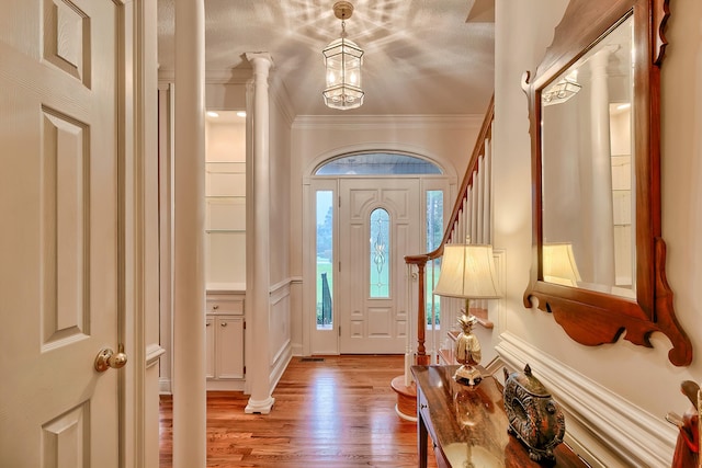 foyer entrance with an inviting chandelier, light hardwood / wood-style floors, a textured ceiling, and ornamental molding