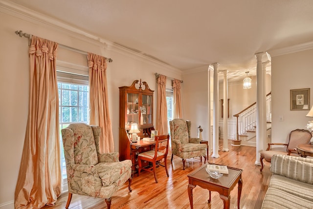 living area featuring decorative columns, light hardwood / wood-style flooring, and ornamental molding