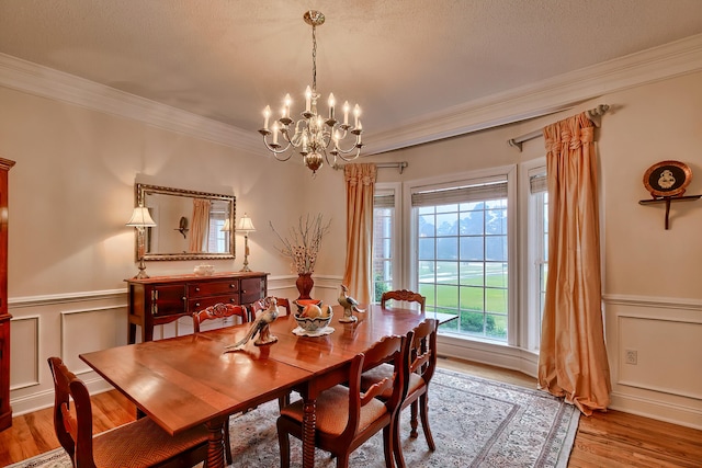 dining area with a textured ceiling, a notable chandelier, crown molding, and light hardwood / wood-style flooring