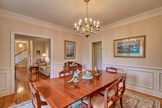 dining area with wood-type flooring, an inviting chandelier, and ornamental molding