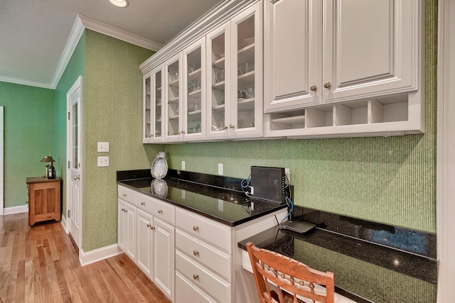 kitchen featuring dark stone counters, white cabinets, light hardwood / wood-style floors, and ornamental molding