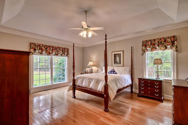 bedroom with ceiling fan, light hardwood / wood-style floors, and a raised ceiling