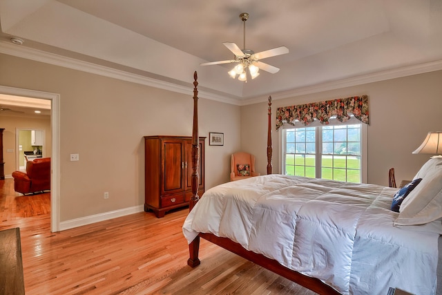 bedroom featuring ceiling fan, light hardwood / wood-style floors, a raised ceiling, and ornamental molding