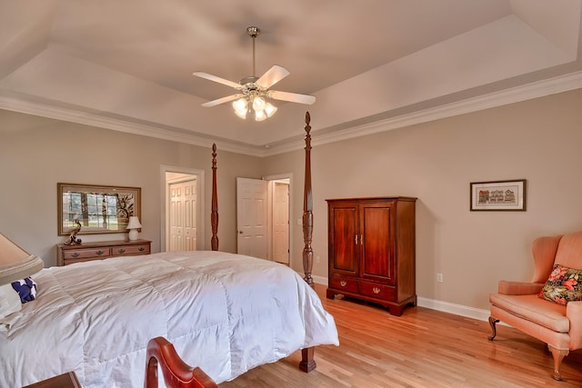 bedroom with ceiling fan, a raised ceiling, light wood-type flooring, and ornamental molding