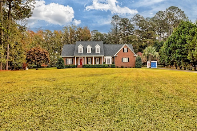 cape cod home featuring a front lawn and a storage shed