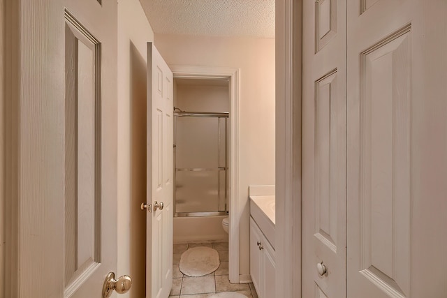 full bathroom with vanity, combined bath / shower with glass door, tile patterned flooring, toilet, and a textured ceiling