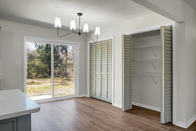 unfurnished dining area with wood finished floors, baseboards, and a chandelier