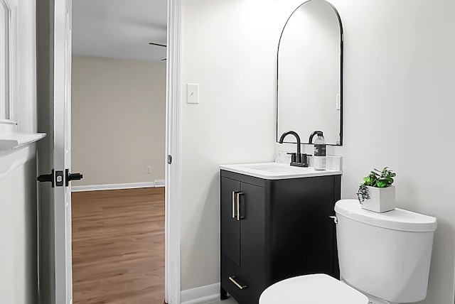 bathroom with baseboards, toilet, wood finished floors, and vanity