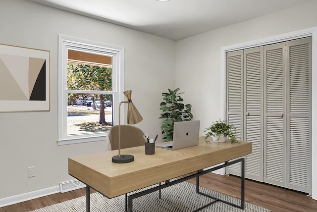 office space featuring visible vents, dark wood-type flooring, and baseboards