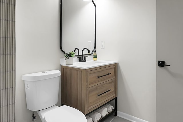 bathroom with baseboards, toilet, and vanity