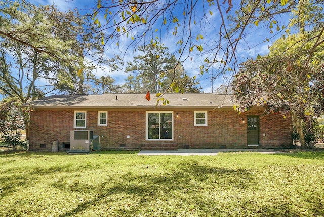 rear view of house with a lawn, brick siding, and crawl space