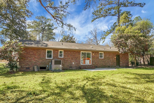 back of property with a lawn, brick siding, and crawl space