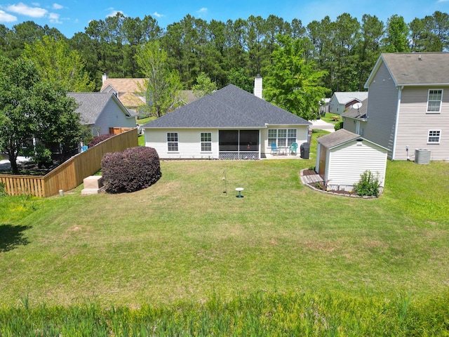 rear view of property with a lawn, central AC unit, a sunroom, an outdoor structure, and a shed