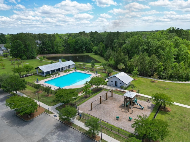 view of pool featuring a lawn, fence, playground community, and a forest view