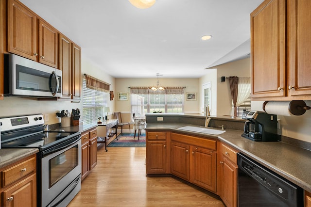 kitchen with appliances with stainless steel finishes, dark countertops, a sink, a peninsula, and a chandelier