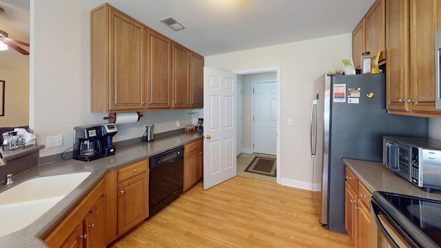 kitchen with a sink, light wood-type flooring, black appliances, and brown cabinets
