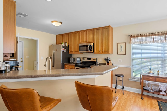 kitchen featuring baseboards, visible vents, a kitchen bar, and stainless steel appliances