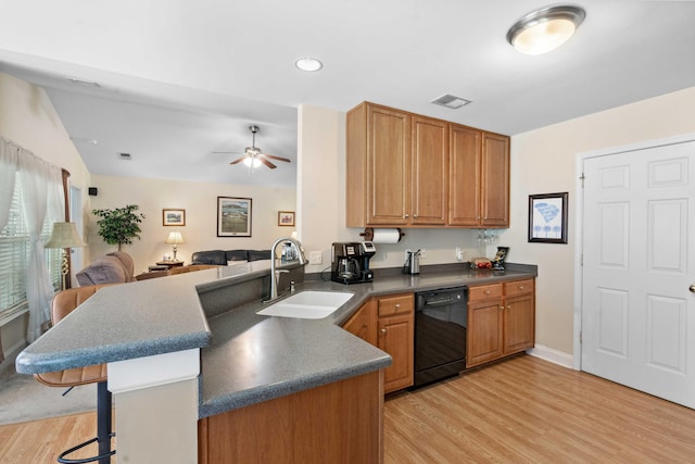 kitchen with visible vents, dark countertops, a sink, light wood finished floors, and black dishwasher