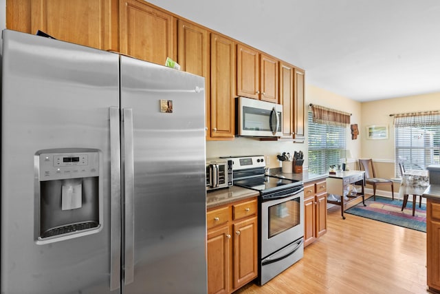 kitchen with a toaster, brown cabinets, stainless steel appliances, and light wood finished floors