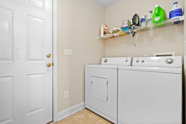 washroom with laundry area, baseboards, washing machine and dryer, and light tile patterned flooring