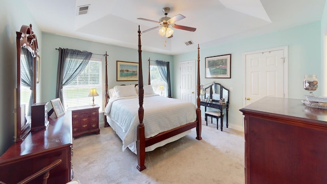 bedroom with visible vents, a ceiling fan, a raised ceiling, and light carpet