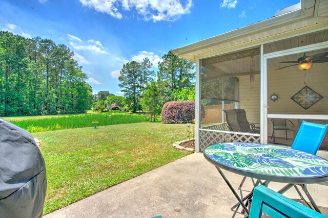 view of yard featuring a patio, ceiling fan, and a sunroom