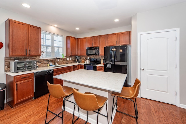 kitchen featuring a kitchen bar, a center island, tasteful backsplash, black appliances, and sink