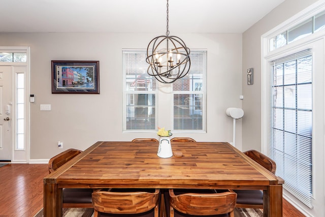 dining area featuring plenty of natural light, wood-type flooring, and a notable chandelier