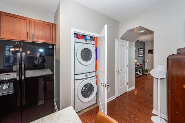 laundry area with dark hardwood / wood-style flooring and stacked washing maching and dryer