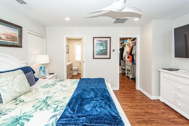 bedroom with a spacious closet, connected bathroom, dark hardwood / wood-style floors, a closet, and ceiling fan