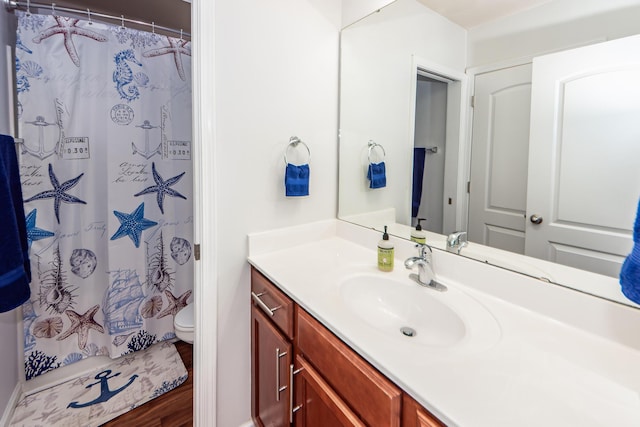 bathroom featuring toilet, vanity, curtained shower, and hardwood / wood-style flooring