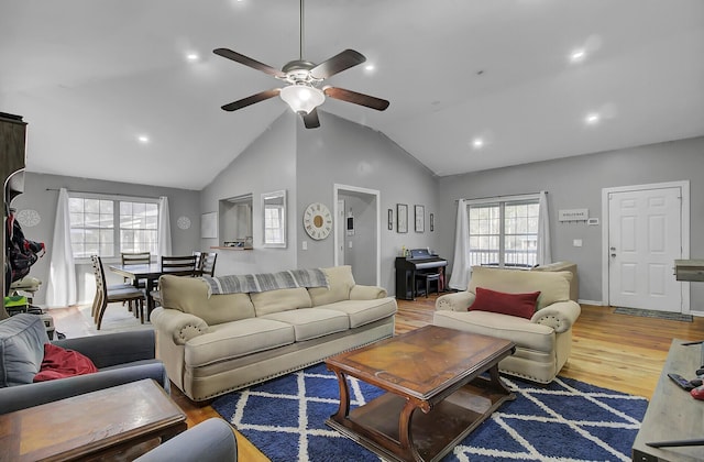 living room with vaulted ceiling, ceiling fan, wood finished floors, and a healthy amount of sunlight