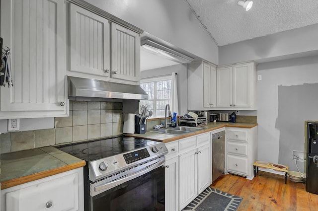 kitchen with stainless steel appliances, a sink, a textured ceiling, under cabinet range hood, and hardwood / wood-style floors