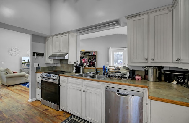 kitchen with light wood-style flooring, under cabinet range hood, stainless steel appliances, a sink, and white cabinetry