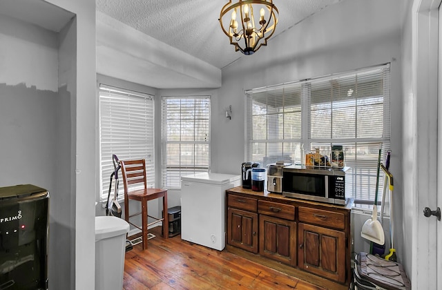 interior space featuring light wood-type flooring, vaulted ceiling, a textured ceiling, and an inviting chandelier