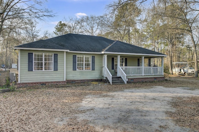 view of front of property featuring driveway, a porch, crawl space, and a shingled roof