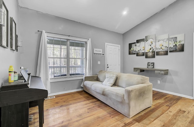 living room featuring light wood-style floors, visible vents, vaulted ceiling, and baseboards