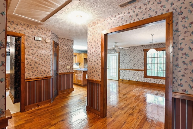 interior space featuring pendant lighting, ceiling fan, light hardwood / wood-style floors, and a textured ceiling