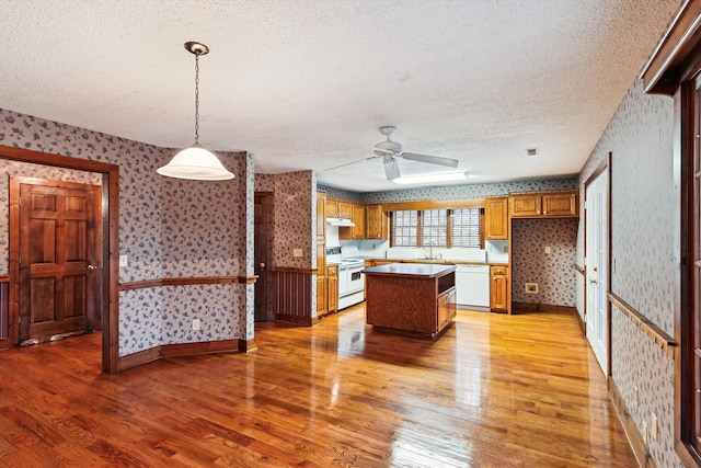 kitchen featuring a kitchen island, decorative light fixtures, white appliances, a textured ceiling, and light hardwood / wood-style flooring