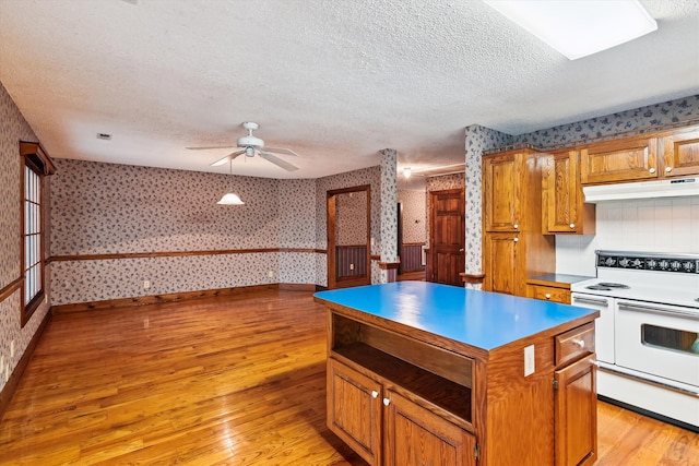 kitchen with double oven range, decorative backsplash, light hardwood / wood-style floors, and a kitchen island