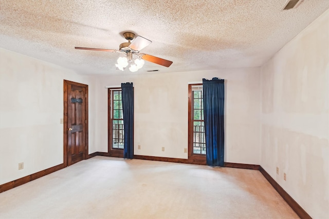 empty room featuring ceiling fan, a healthy amount of sunlight, a textured ceiling, and carpet flooring